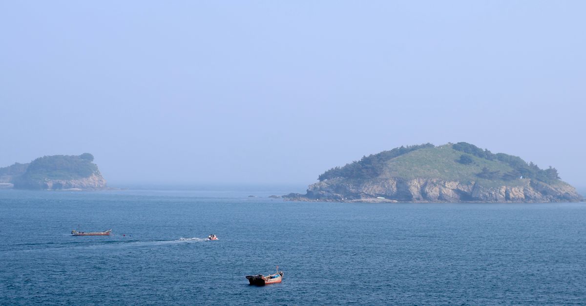 Aerial view of boats moving near lush islands with clear blue waters.