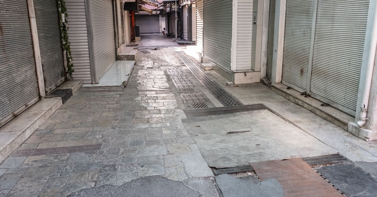 Deserted alley in İzmir with closed roller doors and urban pavement.