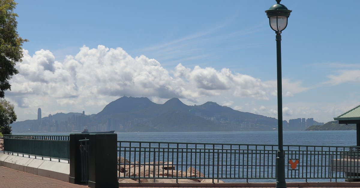 Peaceful view of Hong Kong skyline from a waterfront walkway on a sunny day.