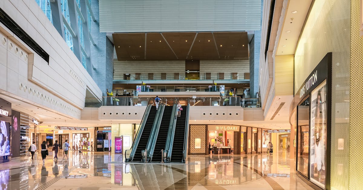 Modern shopping mall interior with escalators and luxury stores in Hong Kong.