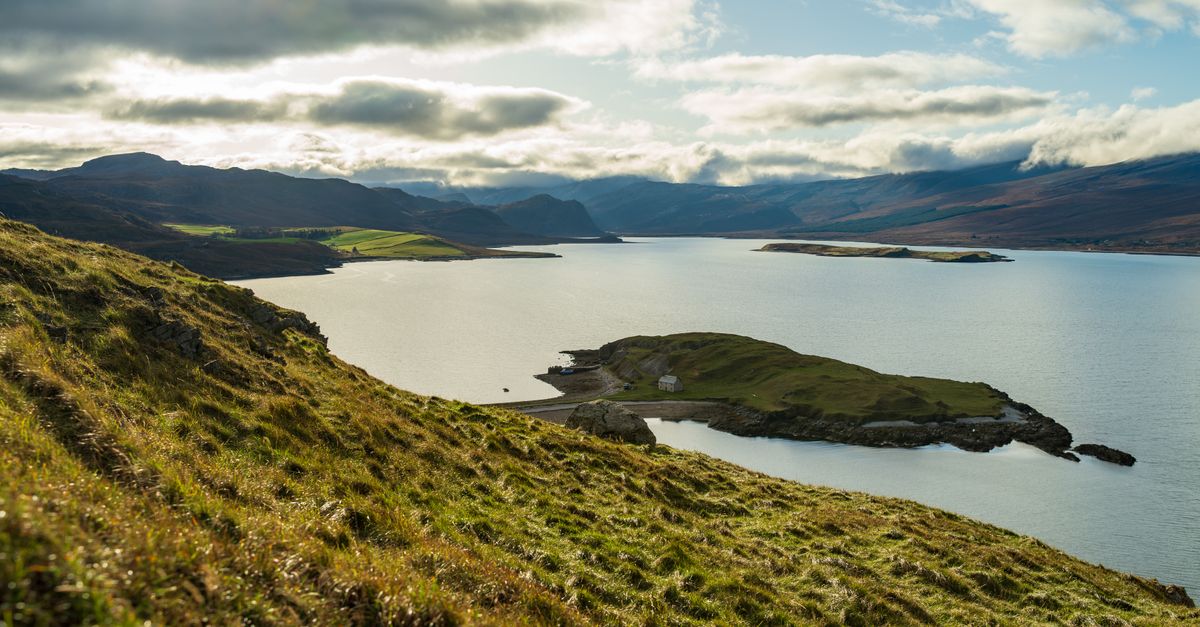 Stunning landscape of a rugged coastline with a serene ocean view under a cloudy sky.