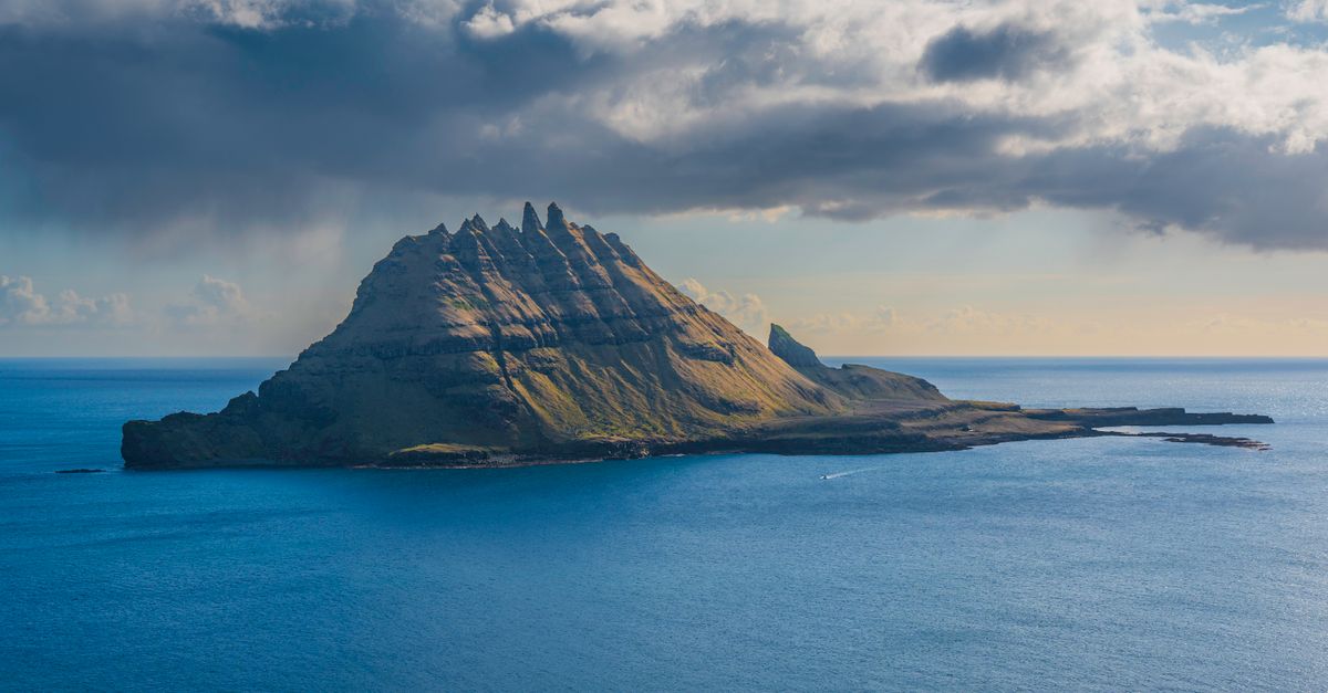 Majestic sea cliff rising amidst the serene ocean, showcasing the natural beauty of the Faroe Islands.