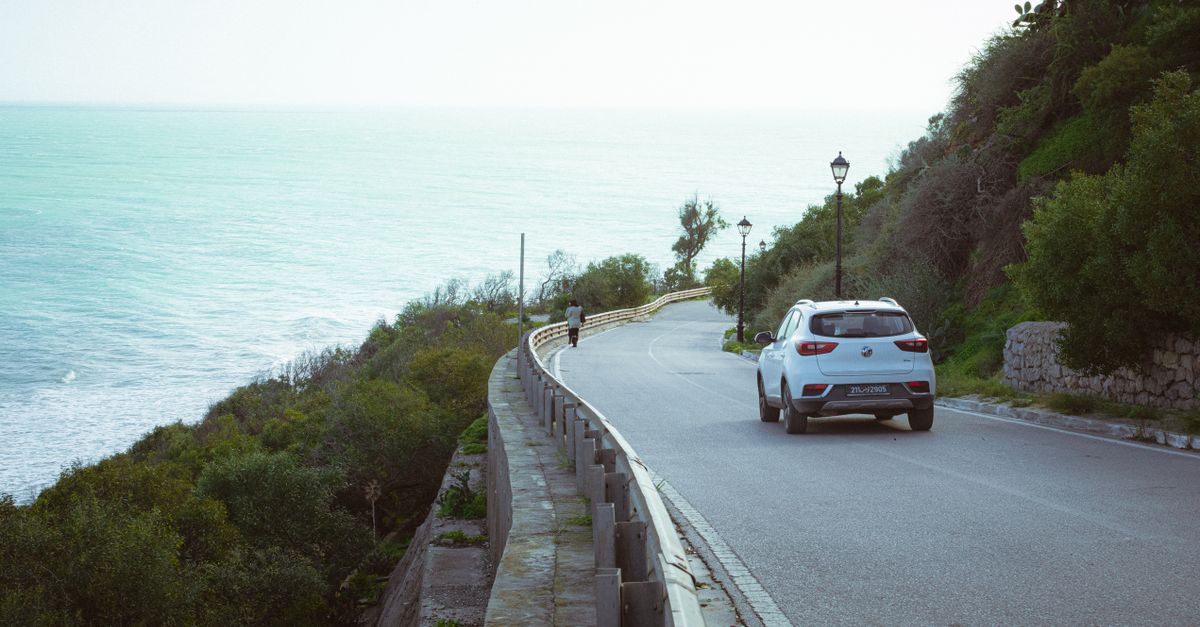 Scenic coastal road in Carthage, Tunisia with ocean view and car.