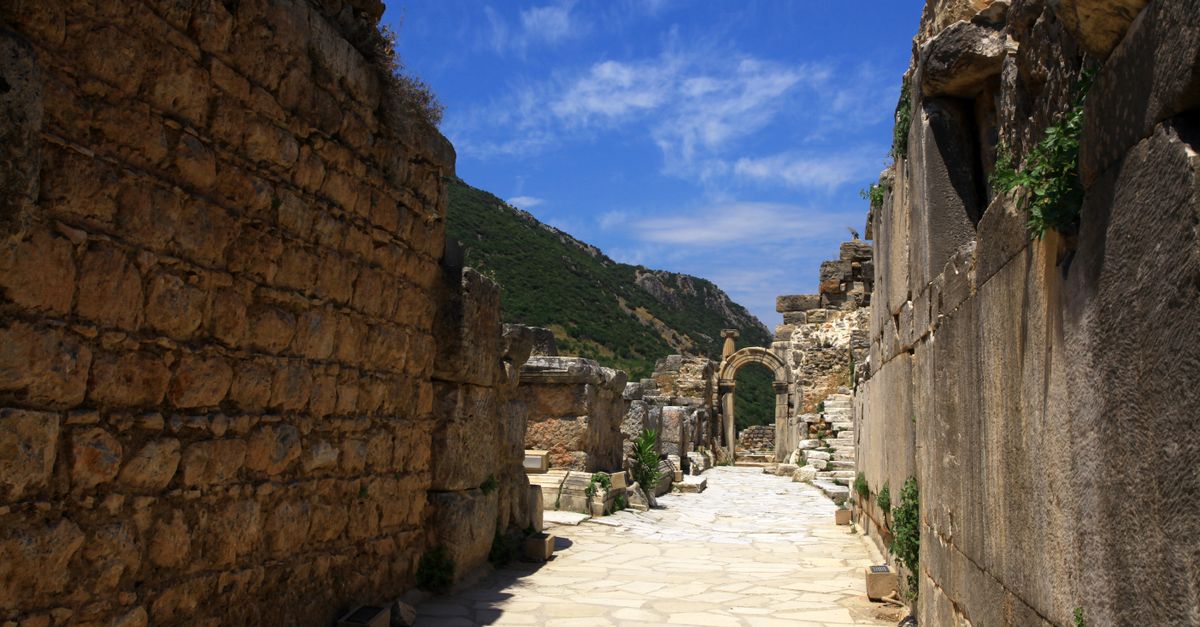 Explore the ancient stone passageways of Ephesus with clear blue skies overhead.