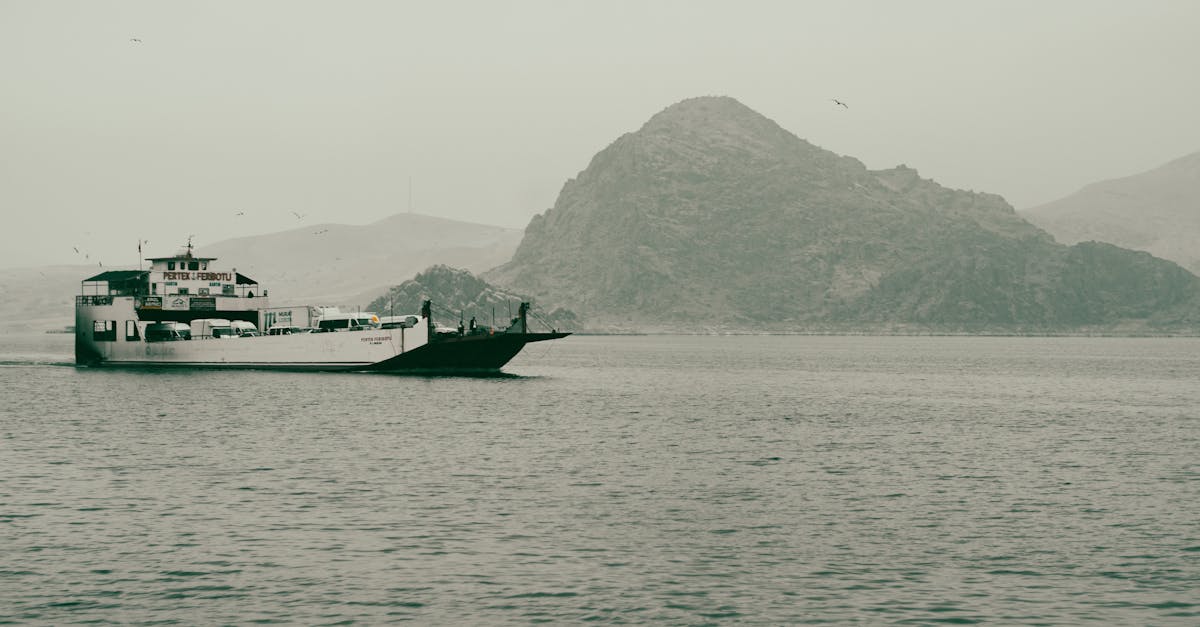 A tranquil ferry travels across the calm sea, framed by distant islands and a misty sky.