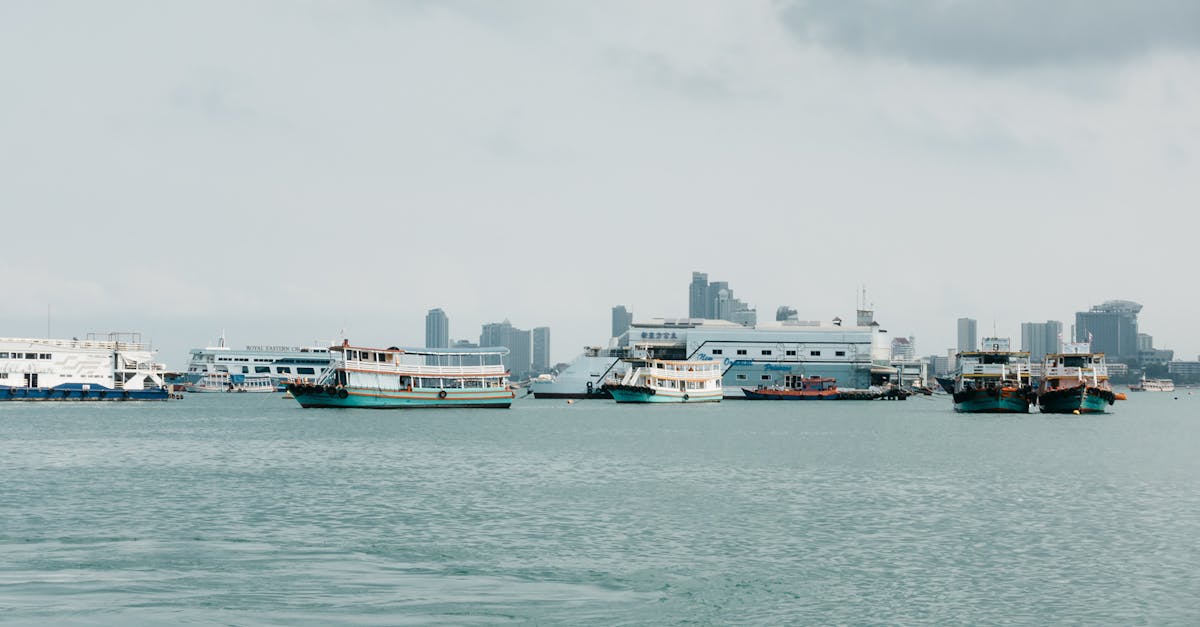 A tranquil city harbor scene with boats and calm water under a cloudy sky.