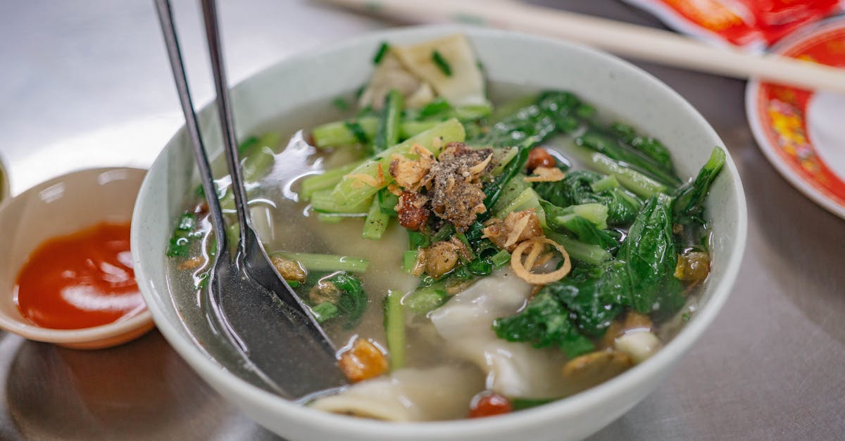Delicious bowl of Asian vegetable soup with fresh greens and dumplings, ideal for a healthy meal.