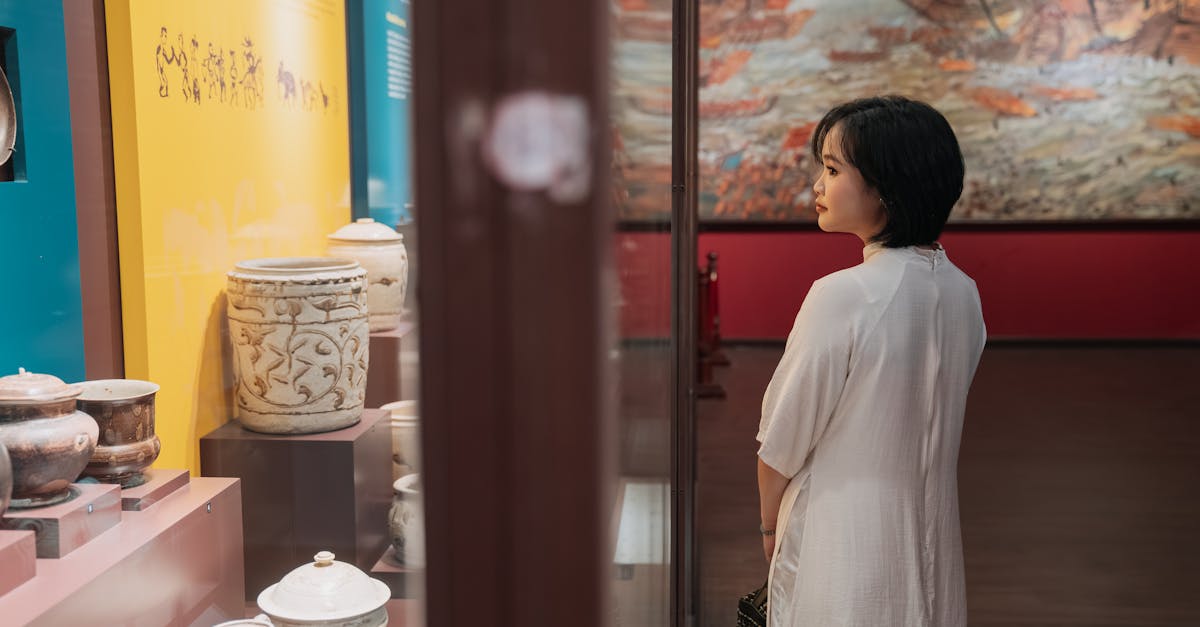 A woman engaging with historical artifacts in a museum exhibit setting, reflecting on culture.