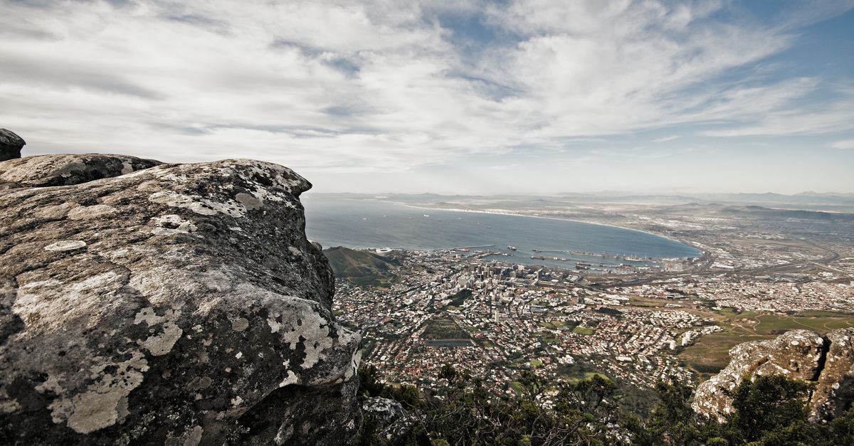 Scenic view of Cape Town cityscape from the rocky edge of Table Mountain with a clear sky.