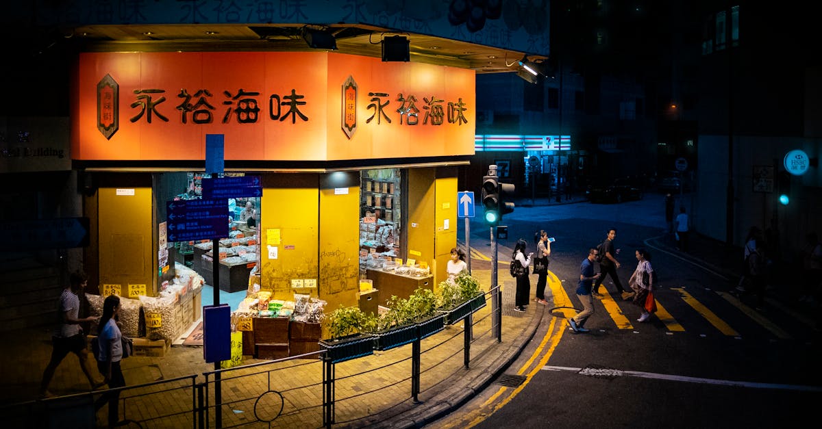 Illuminated Hong Kong storefront by night with pedestrians crossing, capturing vibrant urban life.