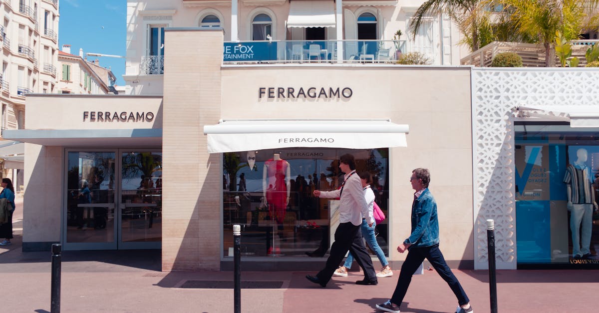 Sunny day view of Ferragamo store in Cannes, France with pedestrians passing by.