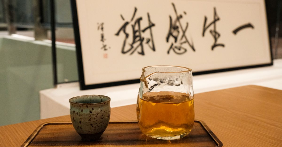 A serene setting with a traditional tea set and Asian calligraphy artwork in the background.