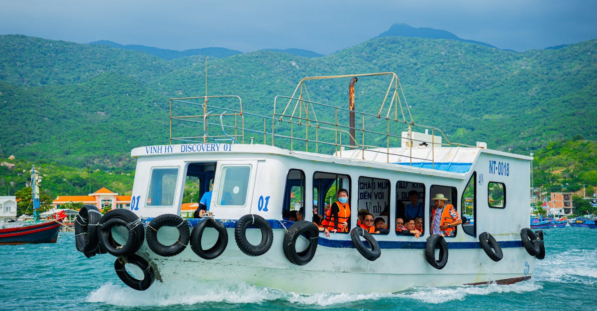 Tourist boat cruising through Vinh Hy Bay with lush green mountains in the background.