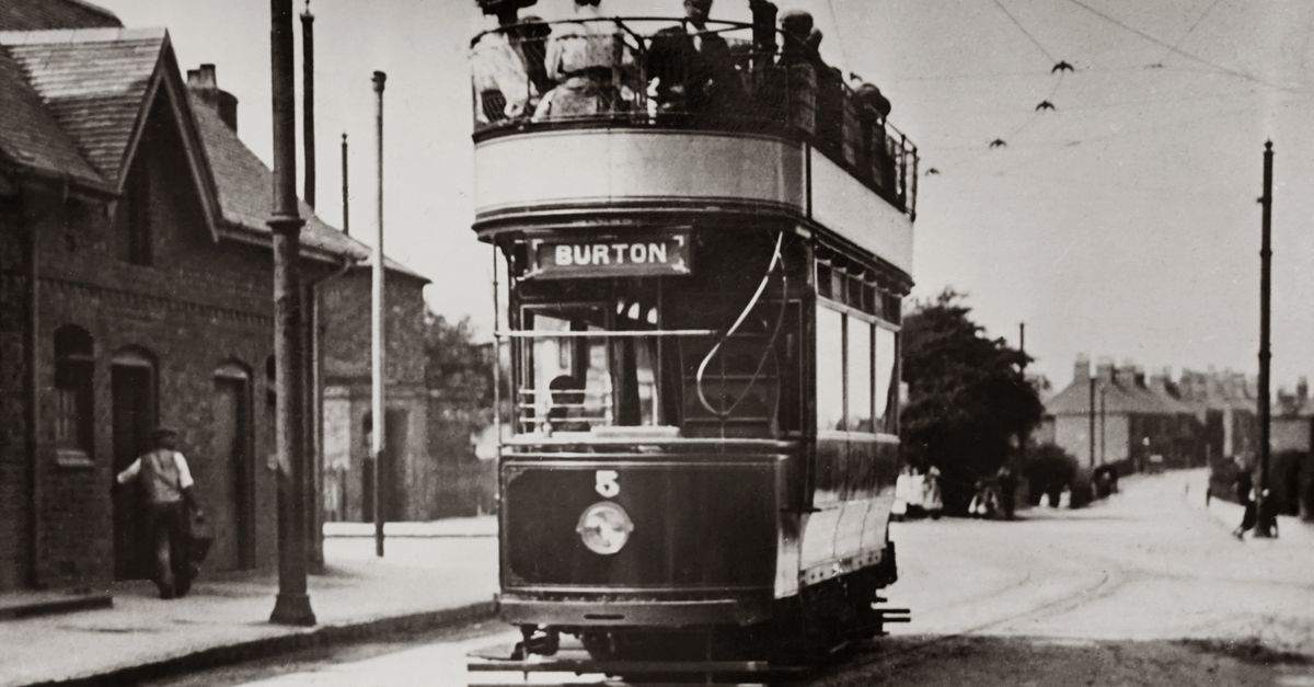 Classic black and white photo of a vintage double-decker tram on an urban street.