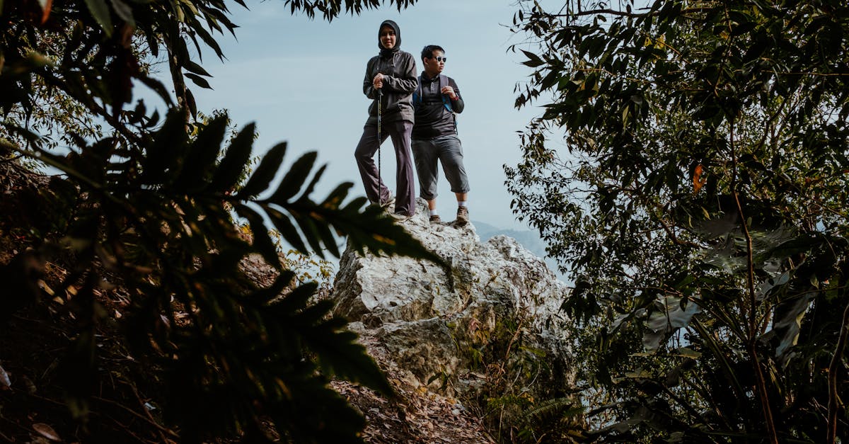 Two hikers stand on a rock surrounded by dense forest in Kuala Klawang.