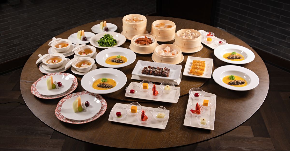Diverse Asian dishes including dim sum and soups beautifully arranged on a large round table.