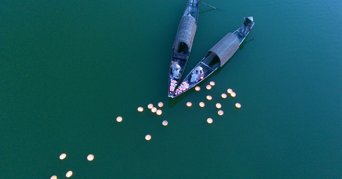 Serene aerial shot of boats with lanterns floating on tranquil water, creating a peaceful scene.