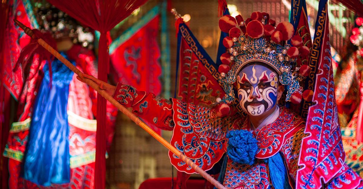 Colorful Peking Opera performer in ornate costume showcasing Chinese theatrical tradition indoors.