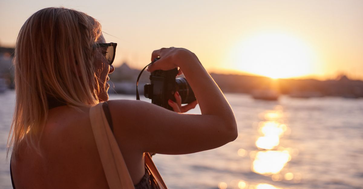 A woman photographing the sunset along the Bosphorus in İstanbul, portraying a serene moment.