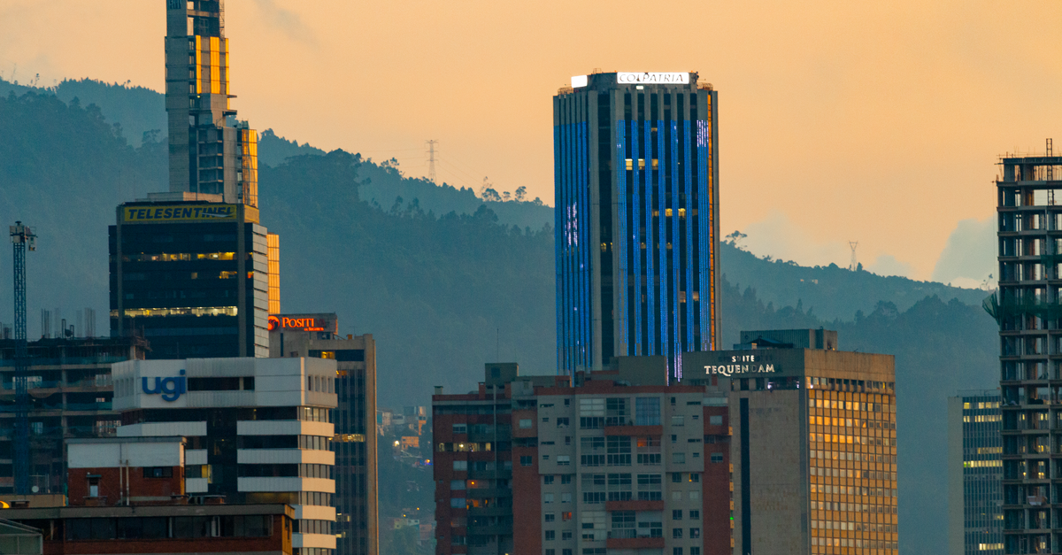 Cityscape of Bogotá featuring skyscrapers and mountains during sunset. Urban skyline with a dramatic backdrop.