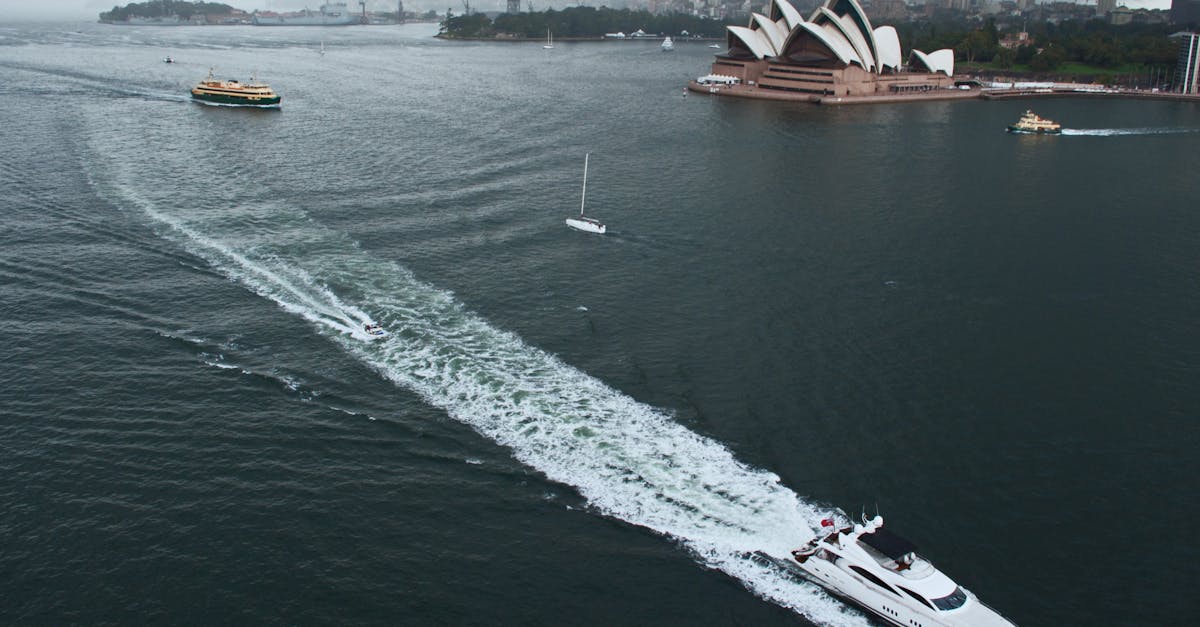 Aerial view of Sydney Opera House with boats sailing nearby on a cloudy day.