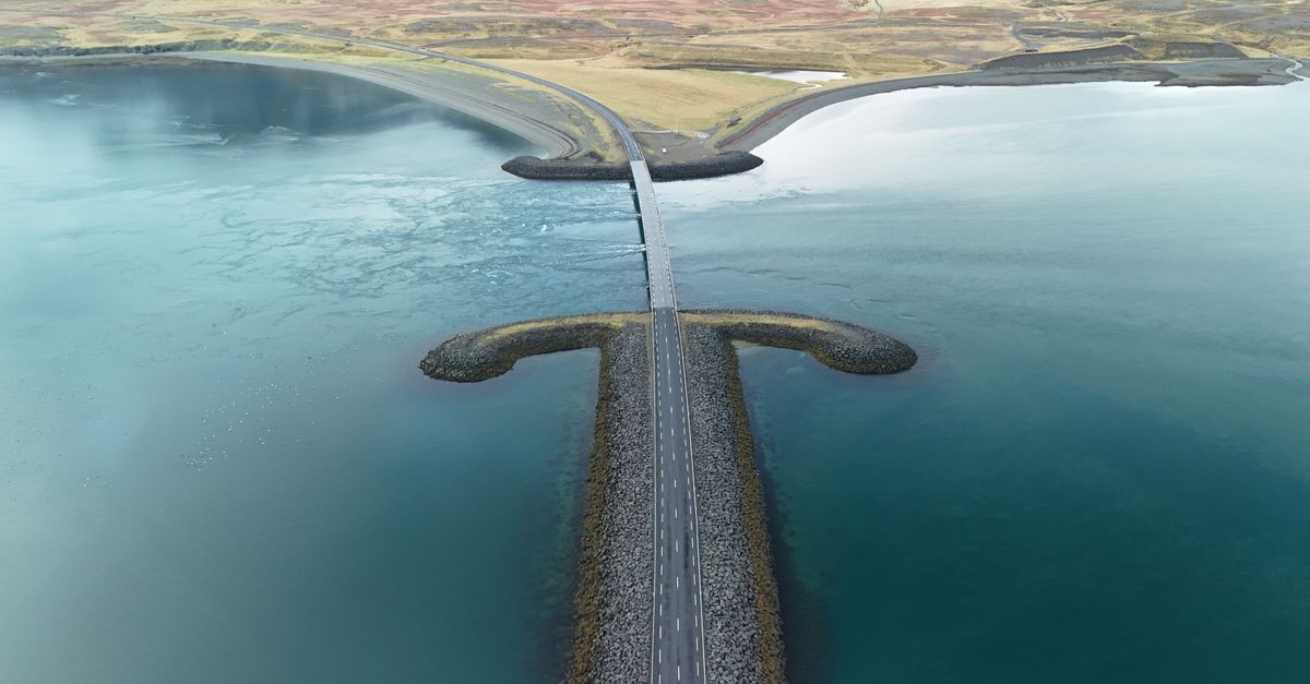 Breathtaking aerial image of a scenic causeway spanning tranquil waters in Iceland, highlighting natural beauty.