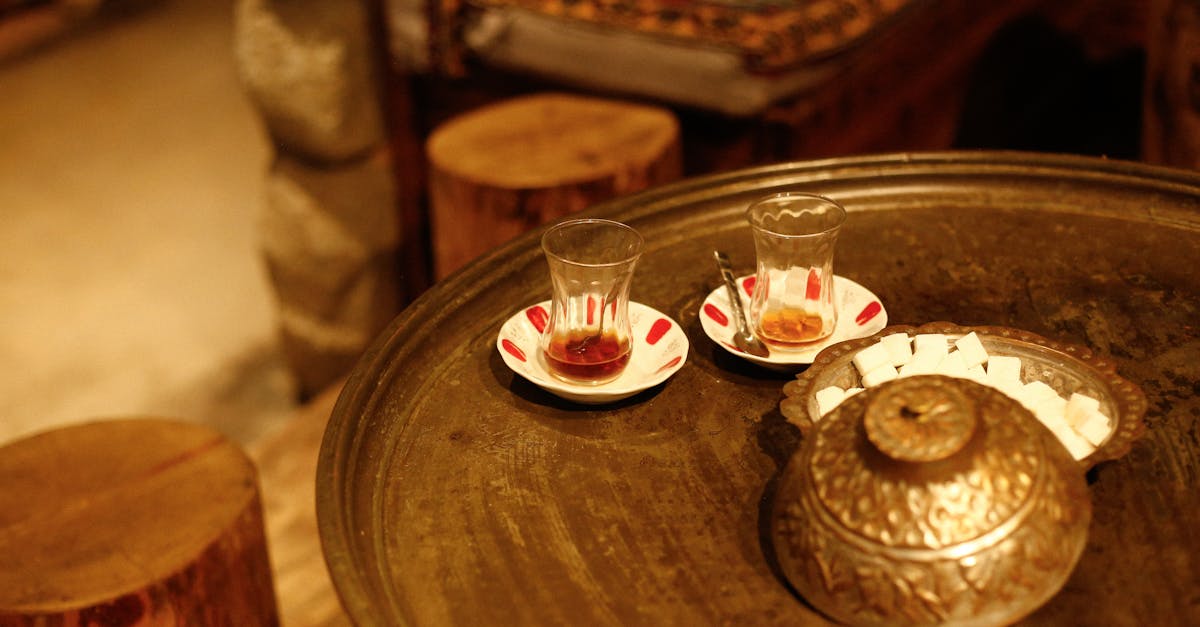 Warm indoor setting featuring two Turkish tea glasses, a decorative pot, and sugar cubes on a rustic table.