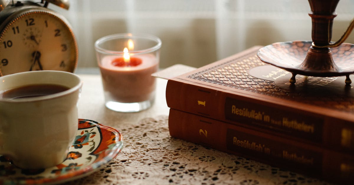 Warm and inviting vintage scene including a coffee cup, books, and candlelight.