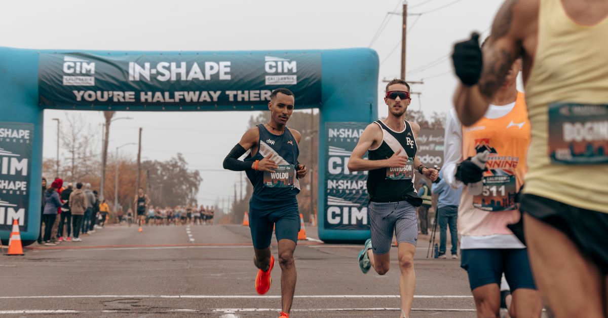 Marathon runners passing halfway mark at a public race on a city street.