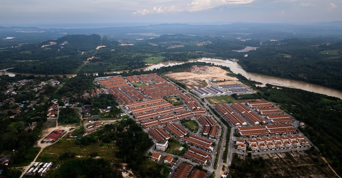 Aerial view of a large housing development surrounded by lush greenery and a river.