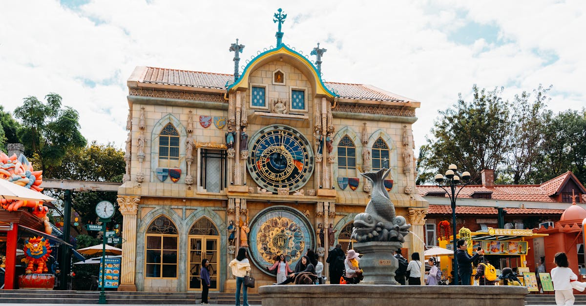 Artistic building at a theme park featuring a large ornamental clock and tourists in front.