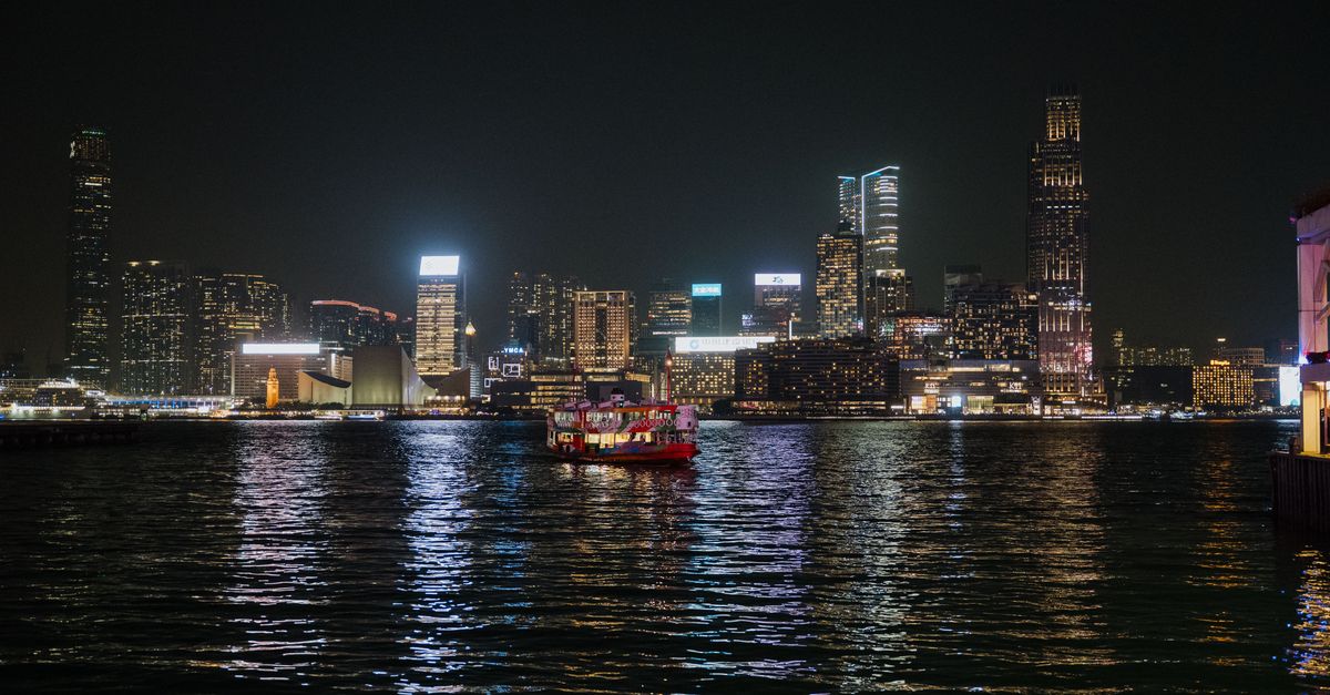 Captivating view of Hong Kong skyline illuminated at night with ferries on Victoria Harbour.