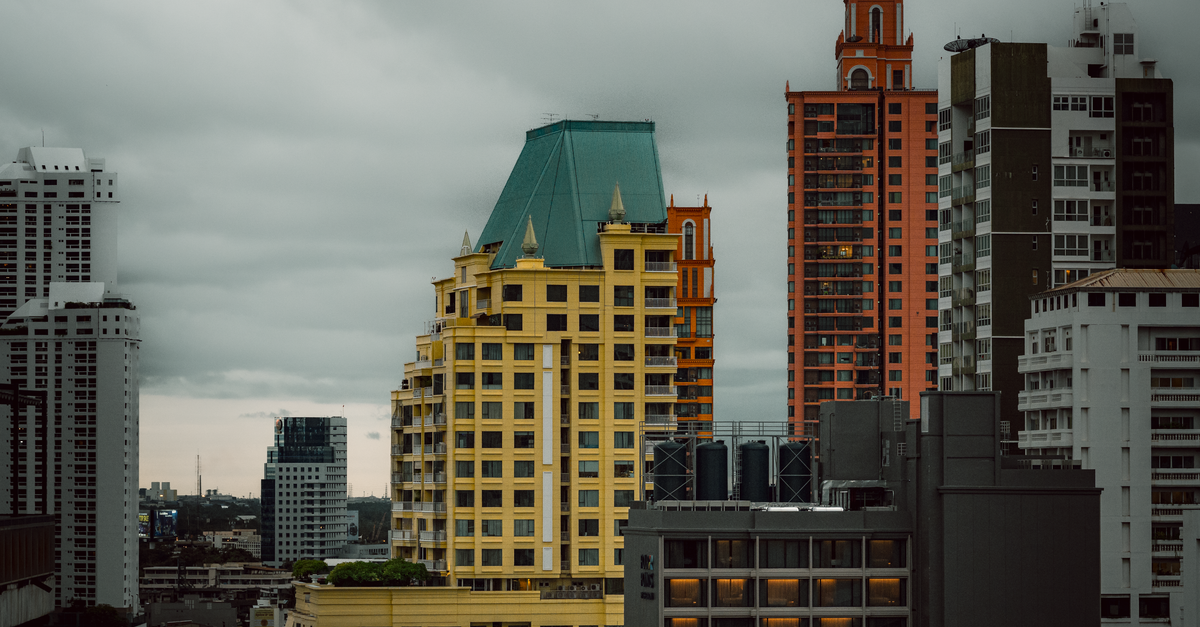A striking view of Bangkok's skyline featuring distinctive colorful buildings against a moody sky.