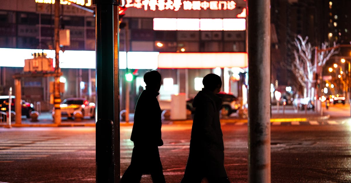 Silhouetted figures crossing a city street at night under vibrant city lights.