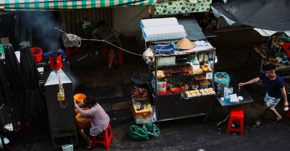 A bustling street food stall in an urban market showcasing local cuisine and street life.