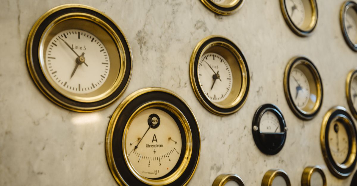 Close-up of vintage brass-rimmed dial gauges mounted on a marble panel.