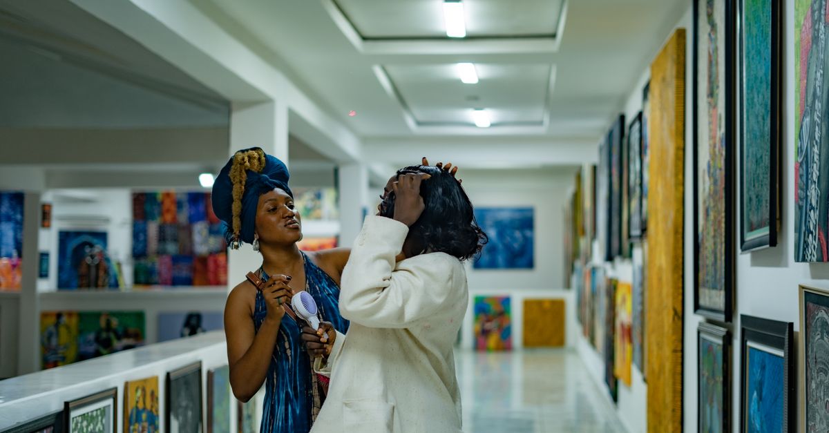 Two adults interacting in a vibrant art gallery filled with colorful paintings.