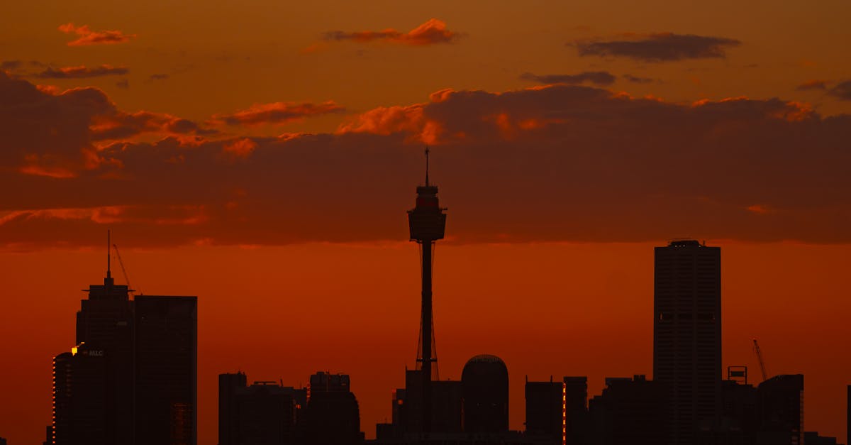 Beautiful silhouette of Sydney skyline with fiery sunset backdrop and clouds.