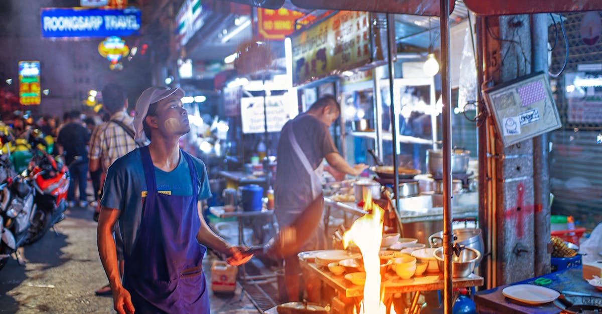 A lively street food vendor in Bangkok bustling with night activity and colorful lights.