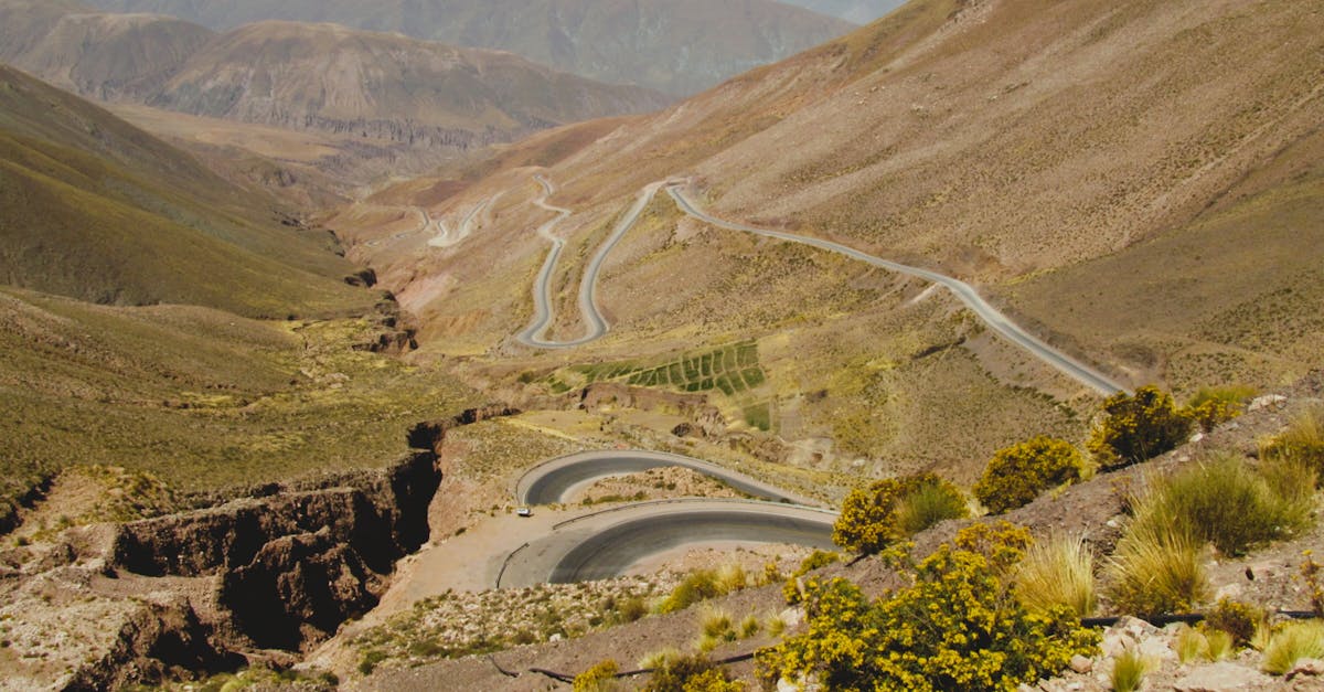 High-altitude winding road through scenic Andes mountains landscape under clear blue skies.