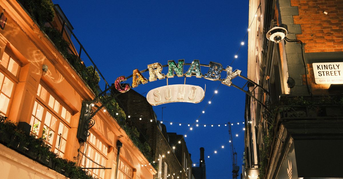 Illuminated Carnaby Street sign in Soho, London, showcasing vibrant nightlife atmosphere.