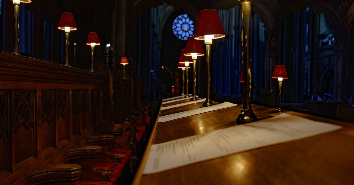 Row of illuminated choir stalls with red lamps in a historic English cathedral.