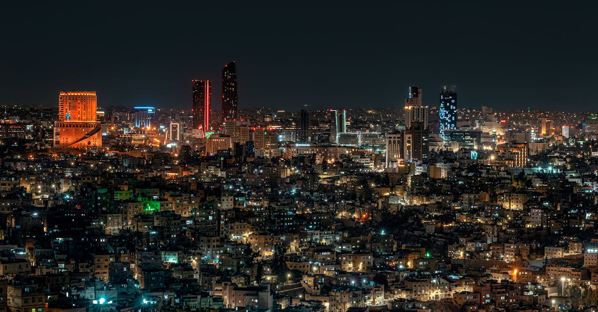 A vibrant night view of Amman city skyline illuminated by city lights, featuring modern architecture.