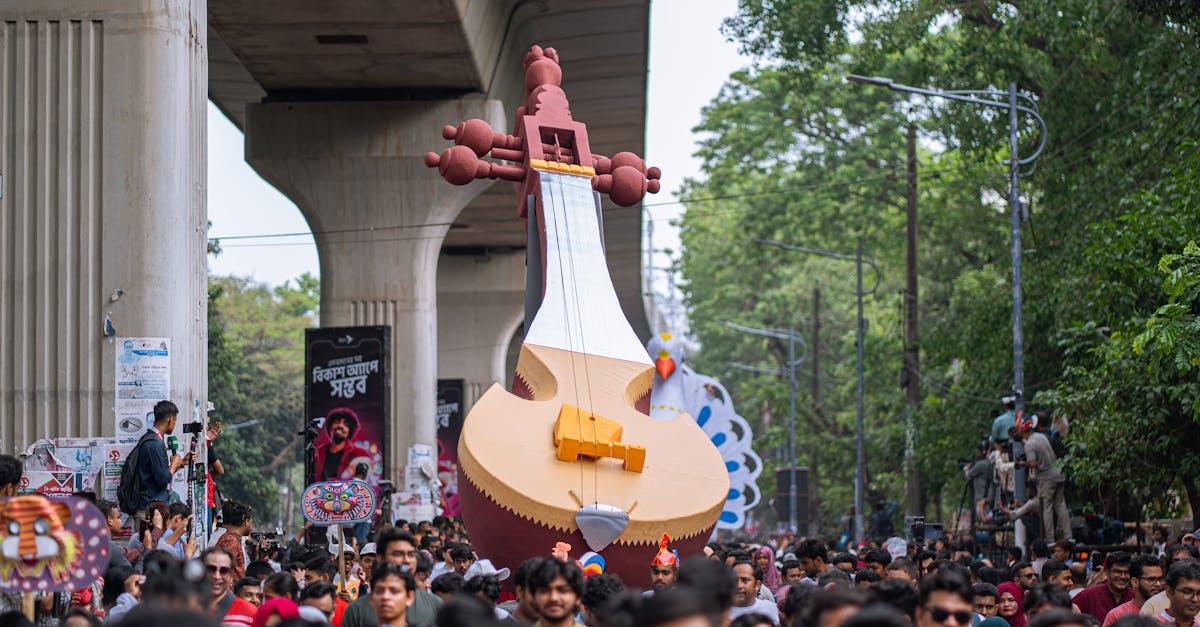 Vibrant street parade featuring a giant sitar float under an urban overpass, celebrating cultural festivities.