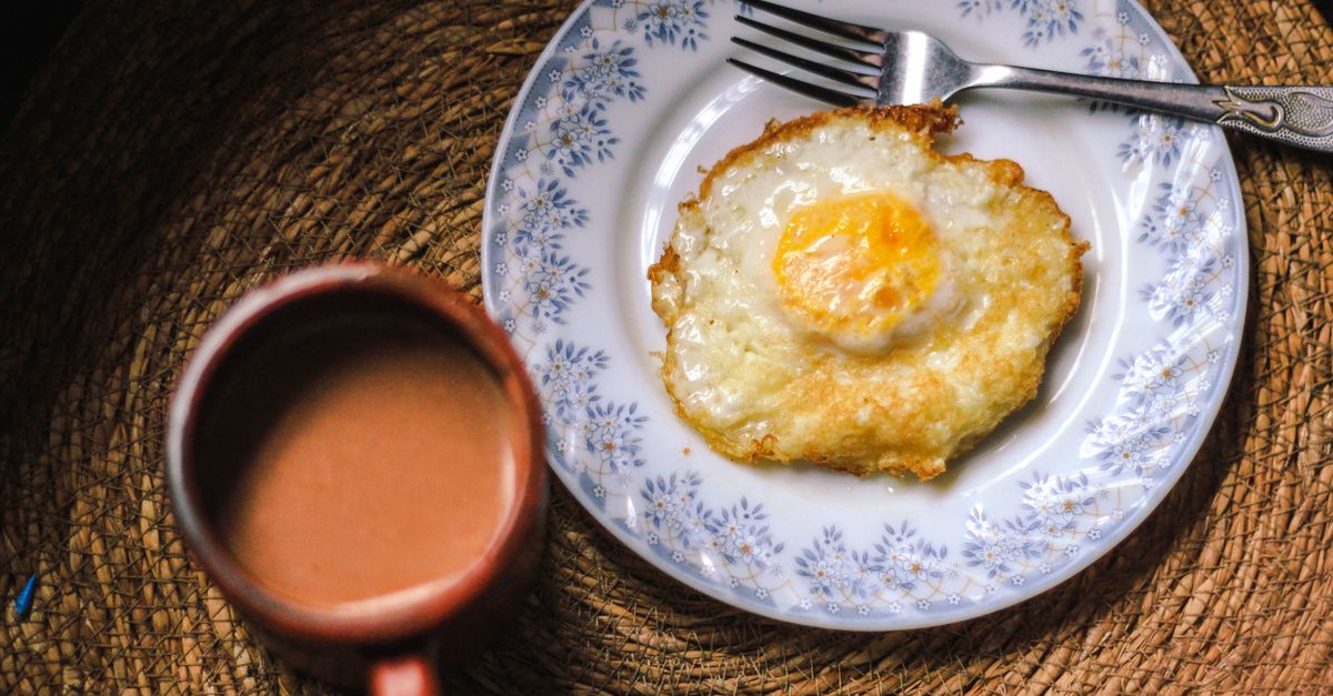 A top view of a fried egg on a plate with a cup of coffee, offering a cozy breakfast scene.