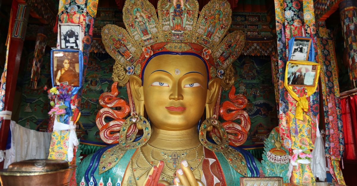 Vibrant statue of Buddha inside a richly decorated Tibetan monastery.