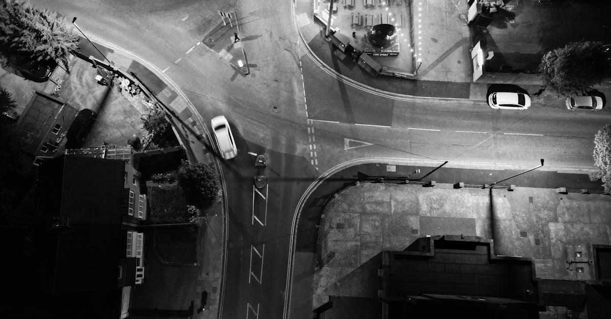 Black and white aerial view of a street intersection at night from above.