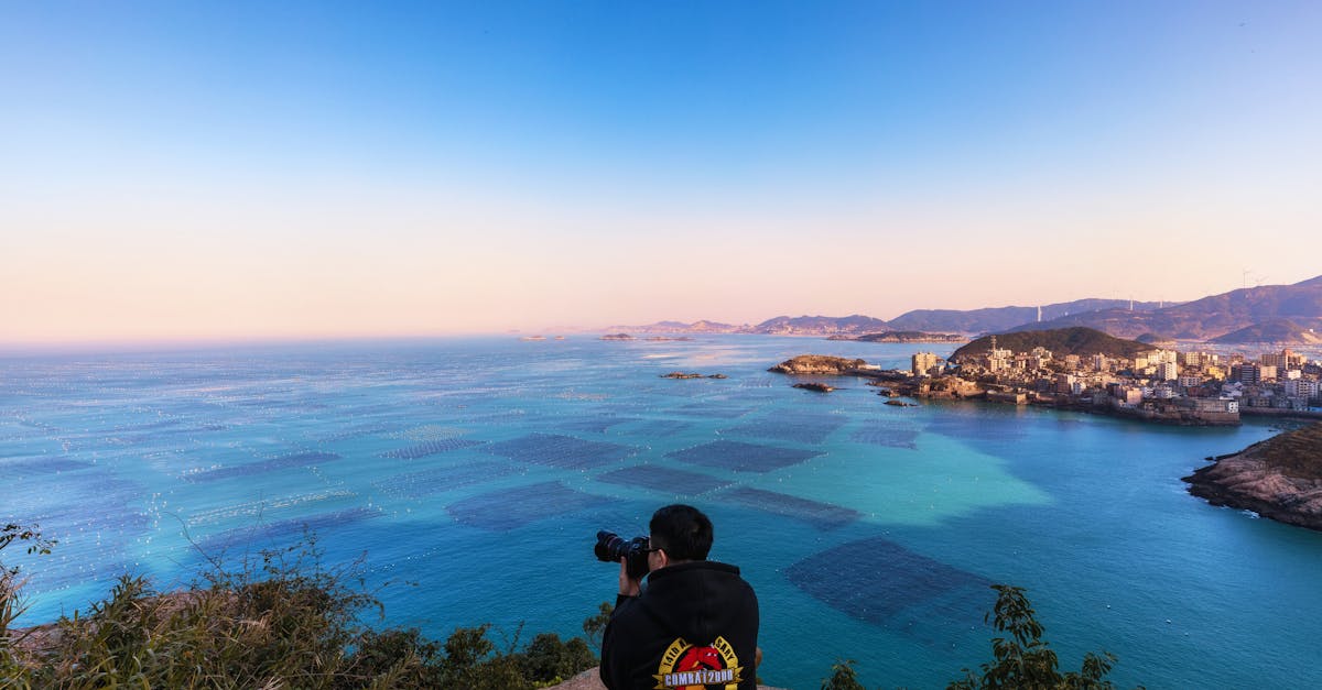 A photographer captures a stunning coastal view with clear blue waters and distant horizon at sunset.