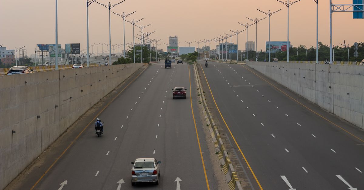 A quiet highway scene at dusk with cars and motorcycles traveling, under a warm evening sky.
