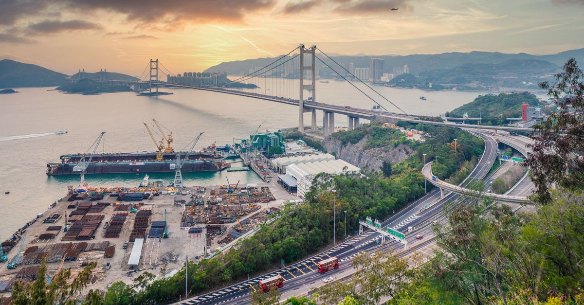 Scenic aerial view of Tsing Ma Bridge, Hong Kong with urban landscape and waterfront at sunset.